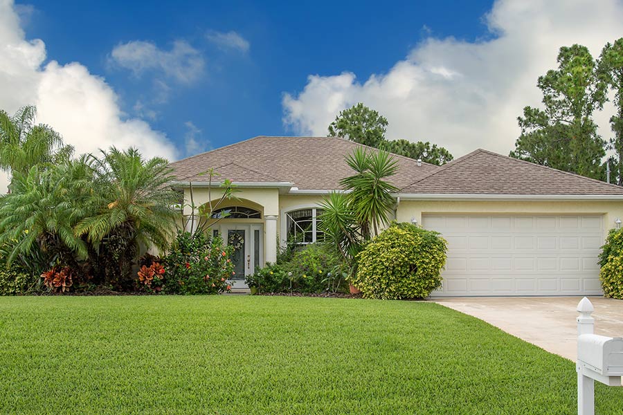 front exterior of off white home with lots of plants and trees in front oviedo fl